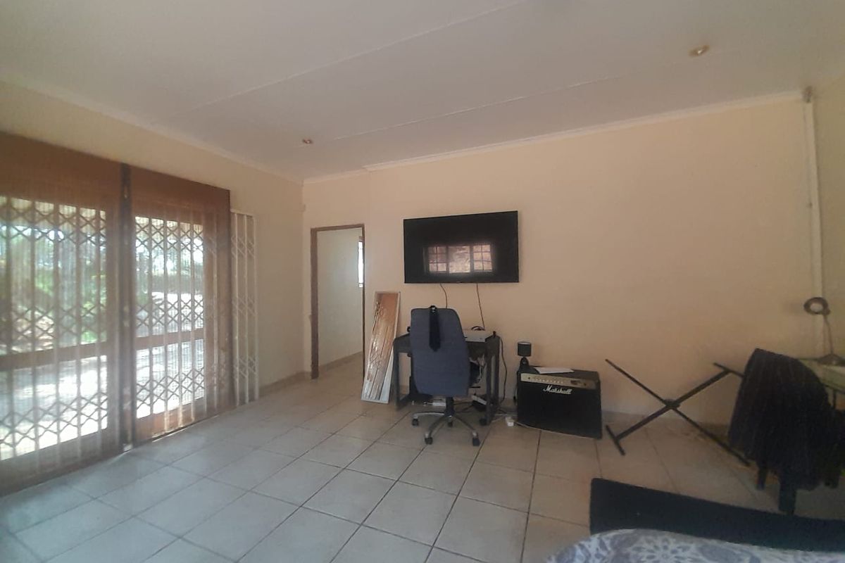 A living room featuring tiled flooring and sliding glass doors with security gates, providing access to the exterior.