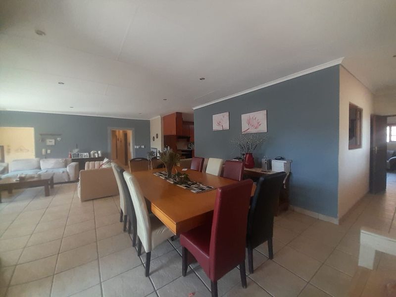Spacious open-plan living and dining area featuring neutral tiled flooring, recessed lighting, and a contemporary blue feature wall.