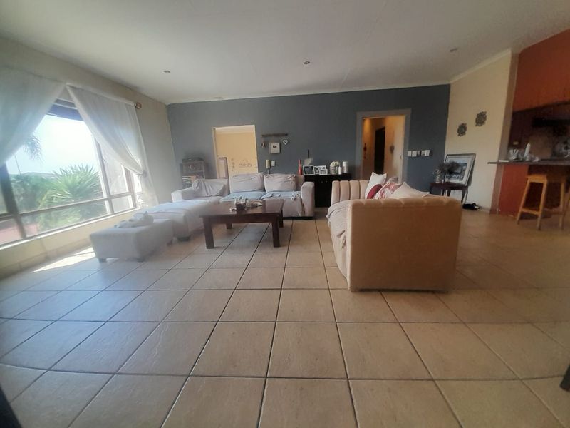 Spacious open-plan living area featuring large windows, neutral tiled flooring, and recessed lighting, offering a bright and versatile layout for family living.
