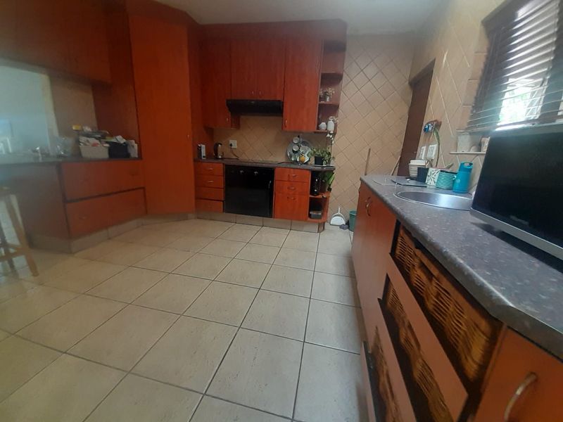 A functional kitchen featuring wooden cabinetry, laminate countertops, tiled flooring, and a built-in oven with an extractor fan.