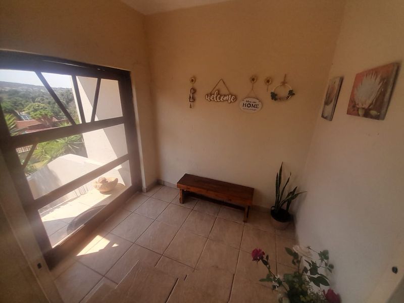 A bright entrance foyer featuring tiled flooring and a large glass-paneled door providing natural light and outdoor views.