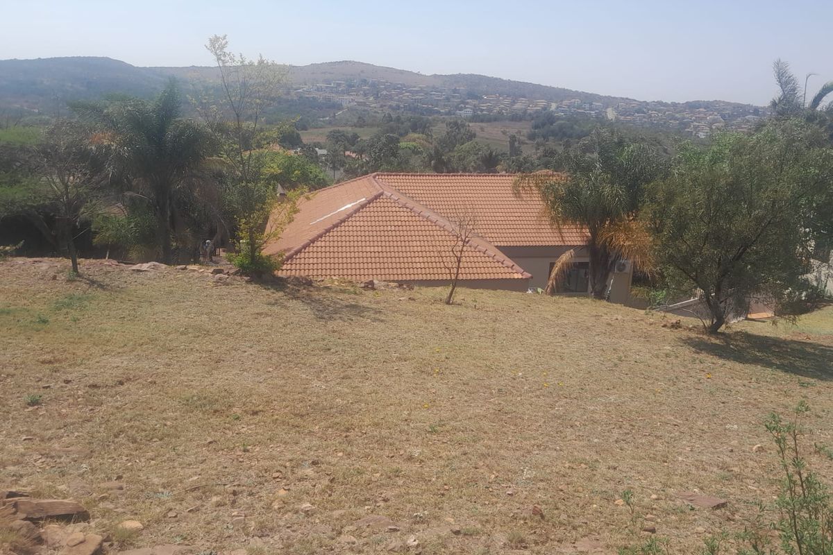 An elevated view of the property featuring a tiled roof and surrounding garden area with scenic landscape views in the background.