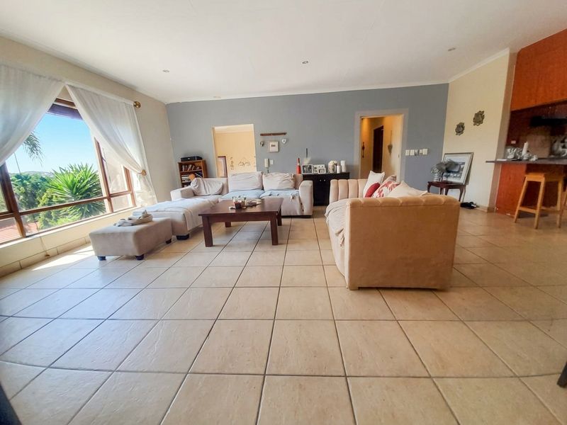 Spacious open-plan living area featuring large windows, tiled flooring, and a breakfast bar connecting to the kitchen space.