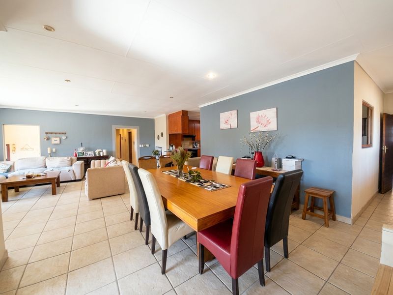 Spacious open-plan living and dining area featuring neutral tiled flooring, recessed lighting, and a functional layout connecting to the kitchen.