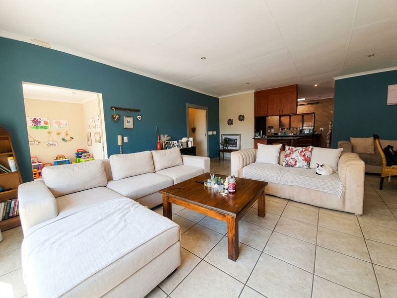 Spacious open-plan living area featuring tiled flooring, recessed lighting, and a connected kitchen with built-in cabinetry and a breakfast counter.