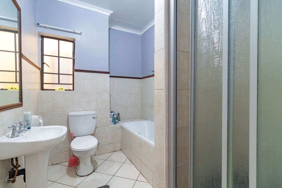 A functional bathroom featuring a pedestal basin, toilet, built-in bathtub, and a separate shower enclosure with tiled finishes throughout.