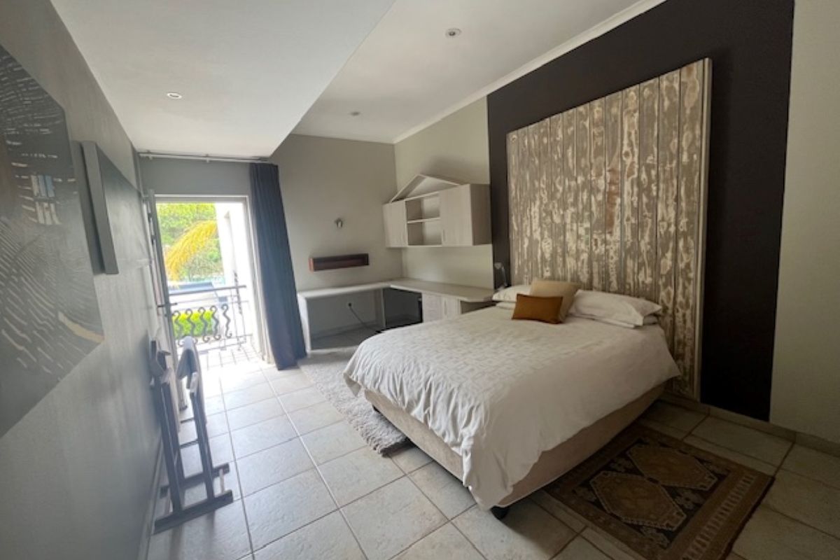 Spacious bedroom featuring tiled flooring, built-in desk and shelving unit, and direct access to a private balcony.