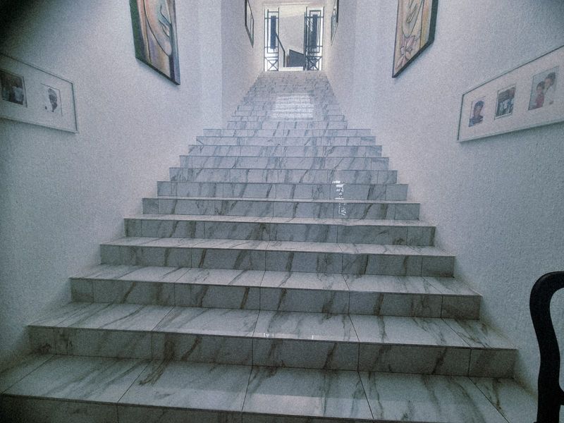 A staircase featuring marble-look tiles leading to an upper level with a metal security gate at the landing.