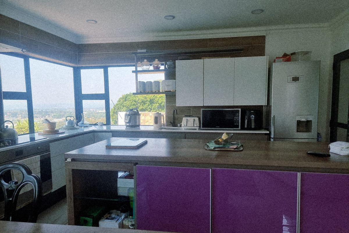 Modern kitchen featuring a central island, ample cabinetry, and large corner windows providing natural light and expansive views.