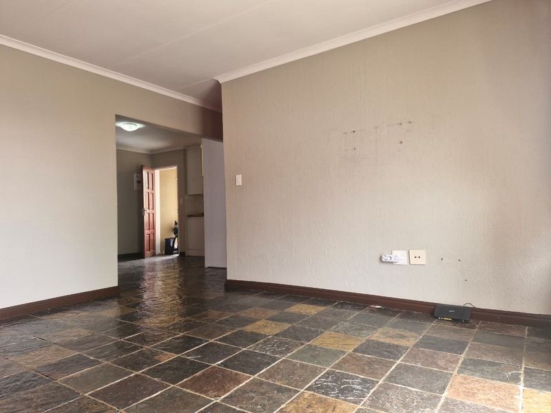 An empty living area featuring textured walls, slate tile flooring, and coved ceilings, providing a blank canvas for potential interior updates.