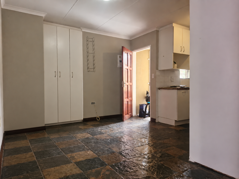 Open plan living area featuring tiled flooring, built-in storage cupboards, and a compact kitchen area with fitted cabinetry.
