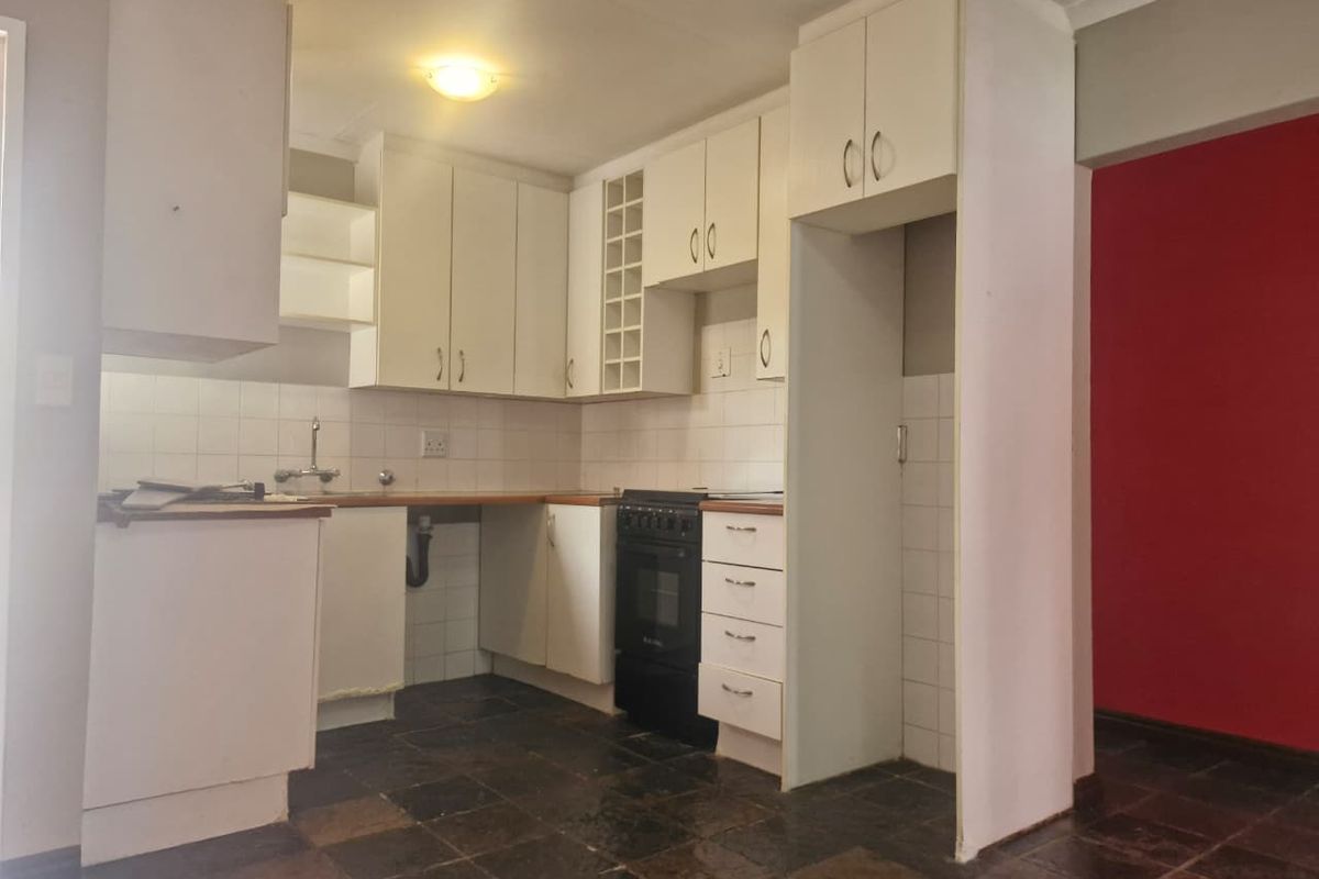 A functional kitchen featuring built-in cabinetry, a tiled backsplash, and a built-in oven, with stone tile flooring throughout.