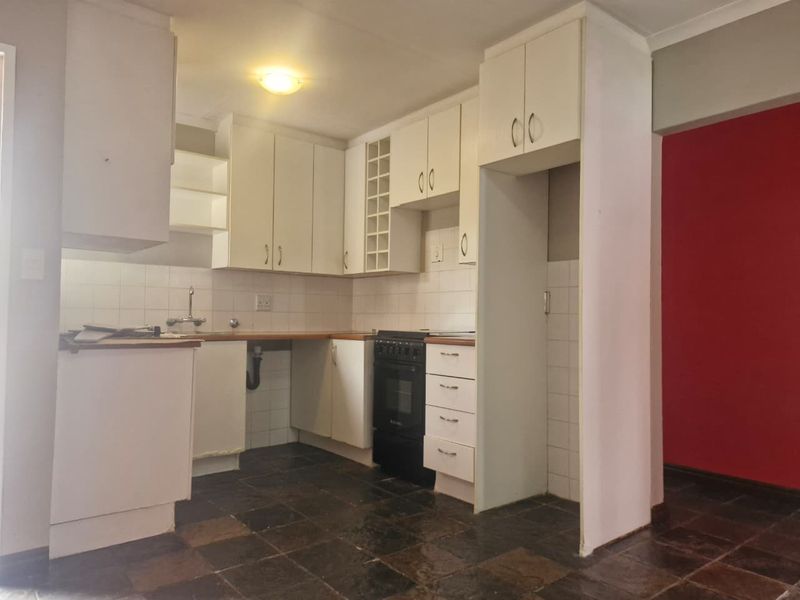 A functional kitchen featuring built-in cabinetry, a tiled backsplash, and a built-in oven, with stone tile flooring throughout.