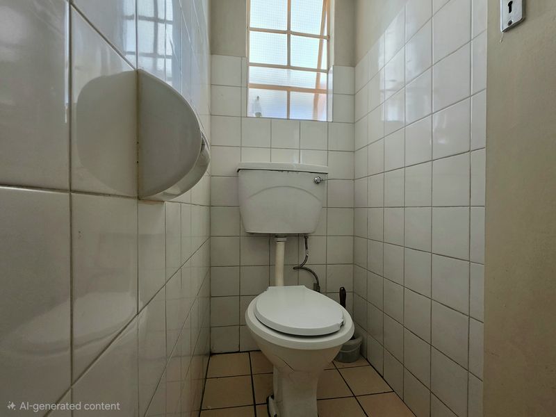A compact, functional bathroom featuring a standard toilet, tiled walls, and tiled flooring, requiring cosmetic updates to improve its overall condition.