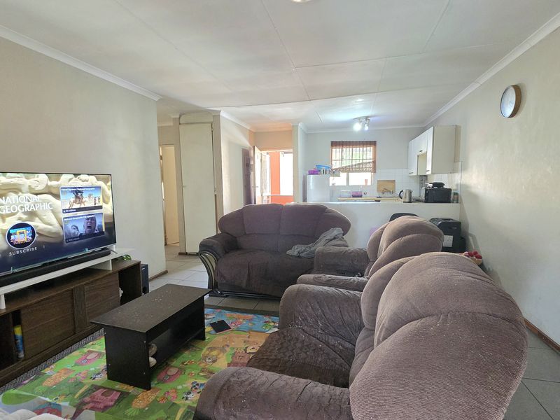 Open-plan living area featuring tiled flooring and a functional kitchen space with built-in cabinetry, offering a versatile layout for daily living.