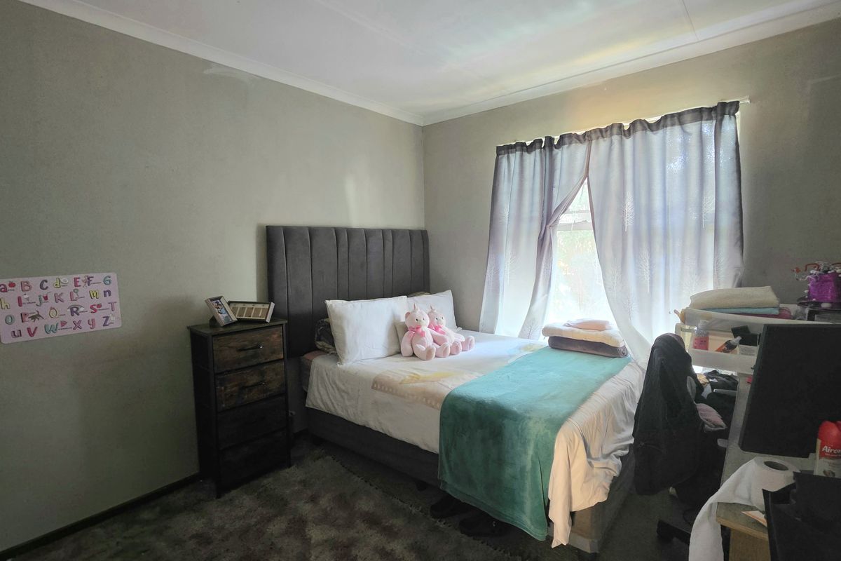 A standard bedroom featuring neutral wall paint, cove cornicing, and a window with curtains.