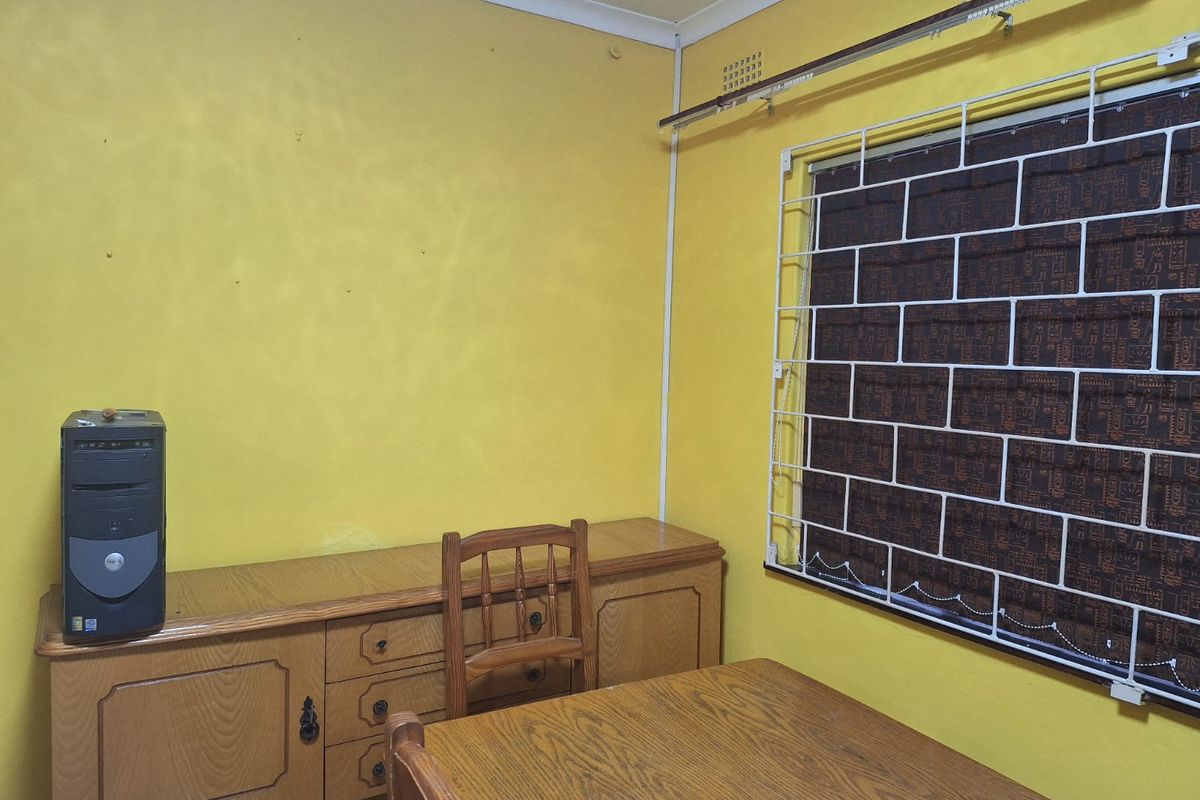 A bedroom featuring yellow walls, a security gate on the window, and a curtain rail.