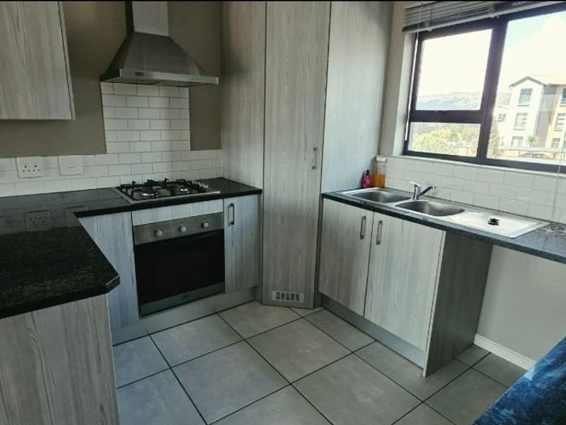 Modern kitchen featuring light wood-grain cabinetry, granite countertops, subway tile backsplash, and integrated stainless steel appliances including a gas hob and oven.