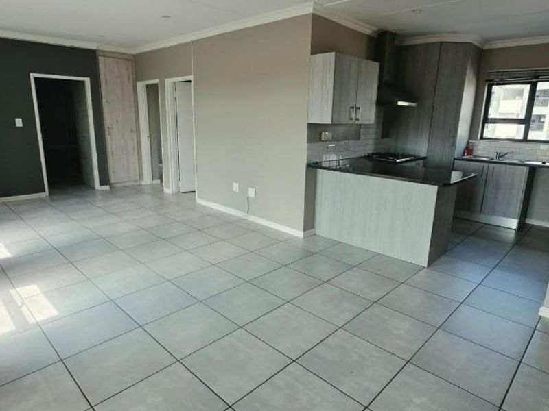 Spacious open-plan living area featuring tiled floors, recessed lighting, and a modern kitchen with granite countertops and built-in cabinetry.