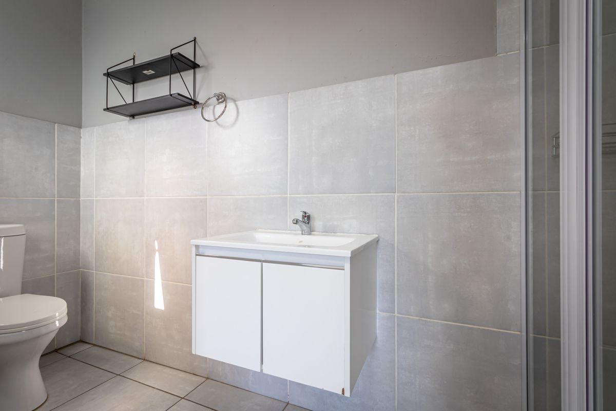 A modern bathroom featuring a wall-mounted vanity with a ceramic basin, tiled walls, and a shower enclosure.