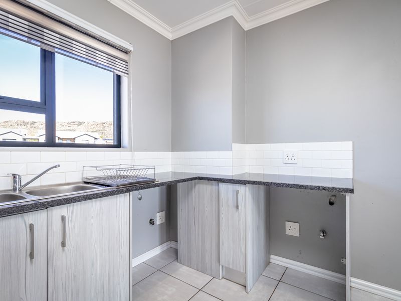 A clean and functional laundry area featuring built-in cabinetry, a stainless steel sink, subway tile backsplash, and dedicated plumbing connections for appliances.