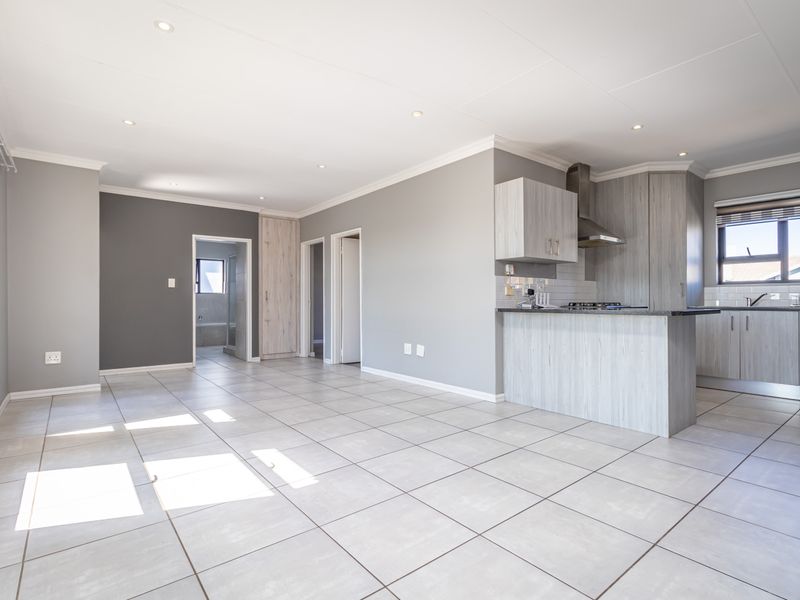 Spacious open-plan living area featuring modern tiled floors, recessed lighting, and a contemporary kitchen with built-in cabinetry, gas hob, and stone countertops.