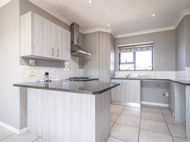 Modern kitchen featuring light wood-grain cabinetry, granite countertops, a gas hob with extractor fan, and a classic subway tile backsplash.