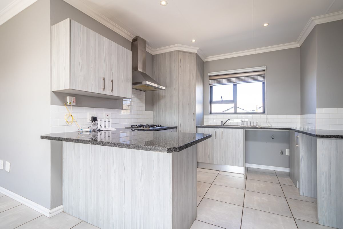 Modern kitchen featuring light wood-grain cabinetry, granite countertops, a gas hob with extractor fan, and a classic subway tile backsplash.