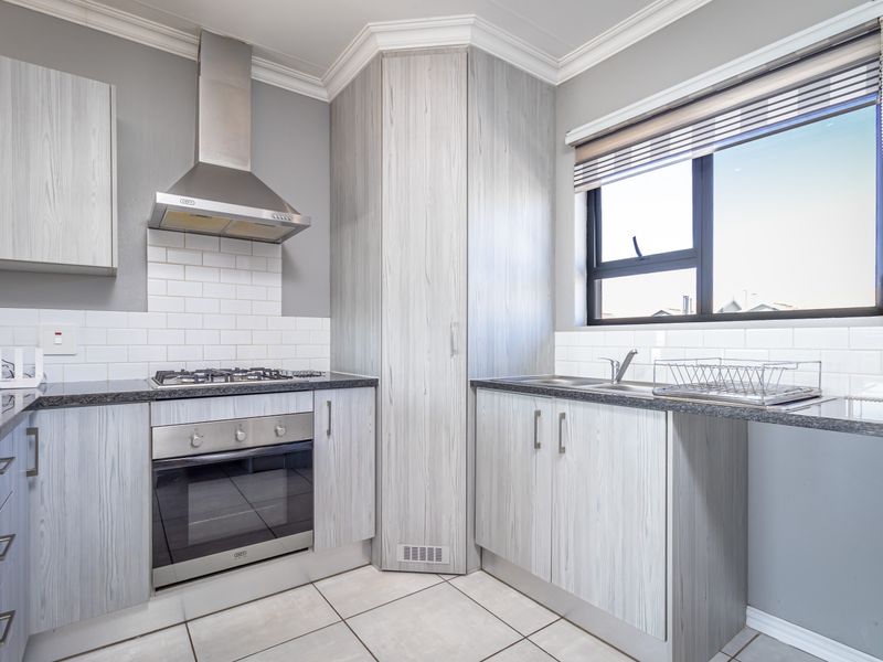 Modern kitchen featuring light wood-grain cabinetry, granite countertops, subway tile backsplash, and integrated stainless steel appliances including a gas hob and oven.