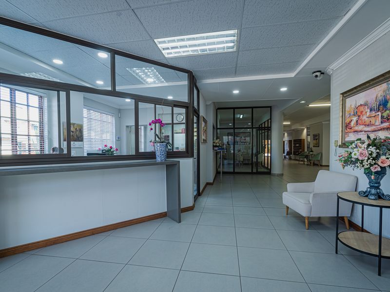 A professional reception area featuring tiled flooring, a glass partition, and integrated lighting, creating a welcoming and well-maintained entrance space.