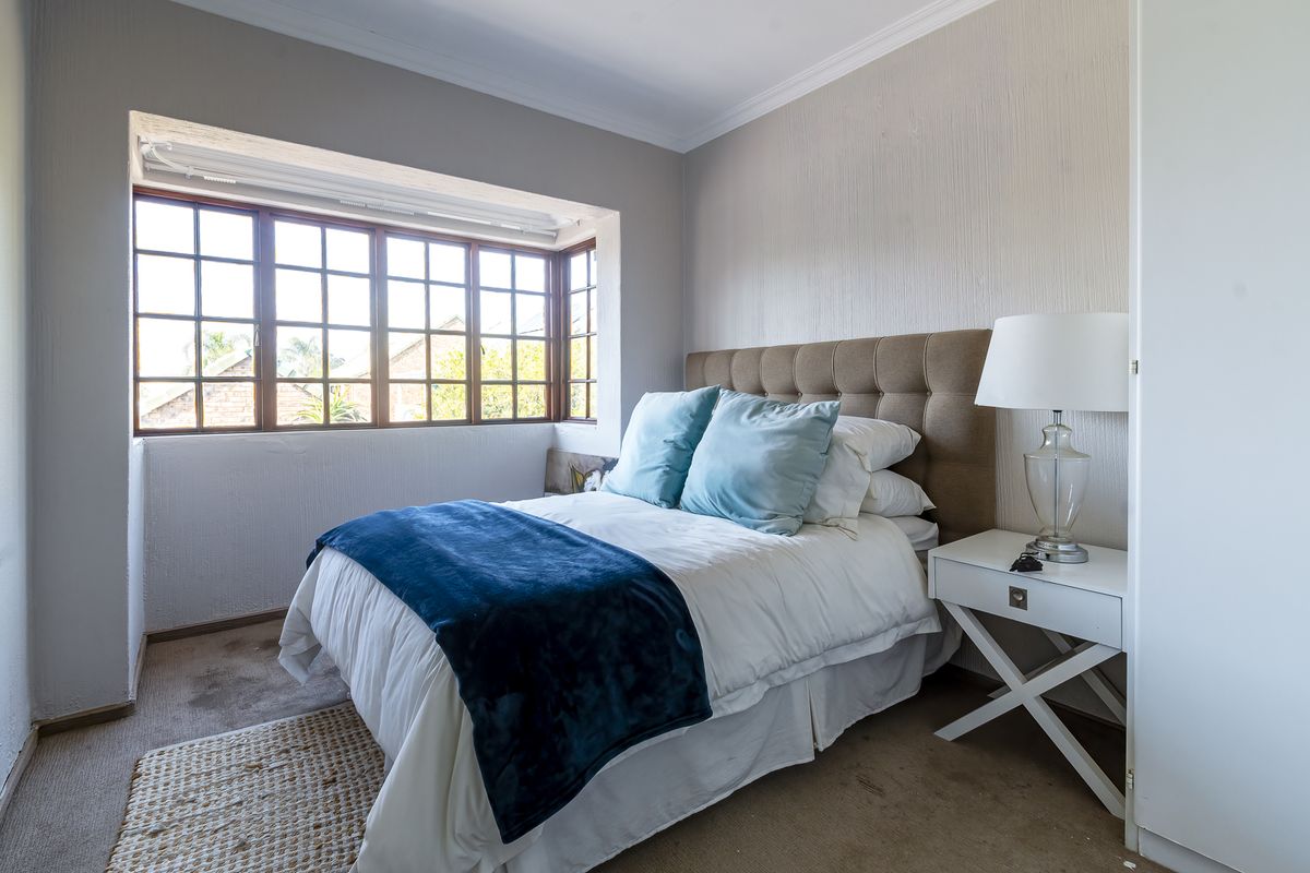 A cozy bedroom featuring a bay window, built-in cupboard storage, and neutral wall finishes, providing a comfortable and functional sleeping space.