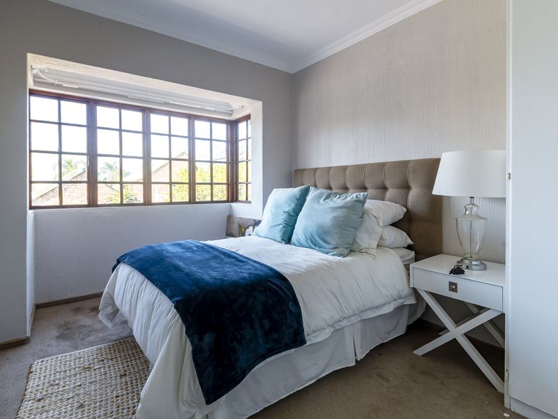 A cozy bedroom featuring a bay window, built-in cupboard storage, and neutral wall finishes, providing a comfortable and functional sleeping space.