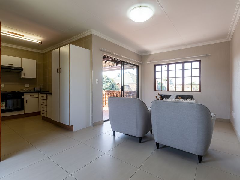 Open-plan living area featuring tiled floors, a functional kitchen with built-in cabinetry, and direct access to an outdoor patio through sliding glass doors.