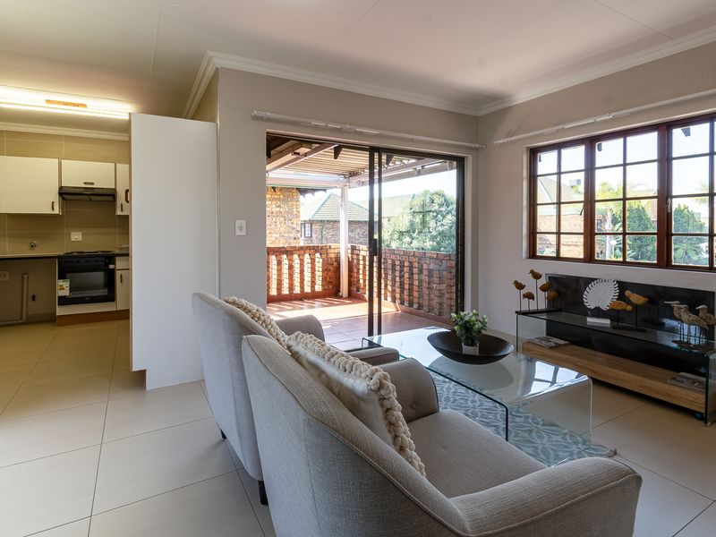 Open-plan living area featuring tiled floors, a functional kitchen with built-in cabinetry, and direct access to a private balcony through sliding glass doors.
