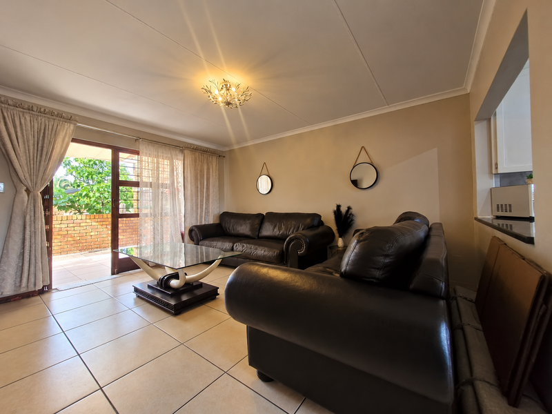 A living room featuring tiled flooring, a coved ceiling, and a sliding glass door providing access to an outdoor patio area.