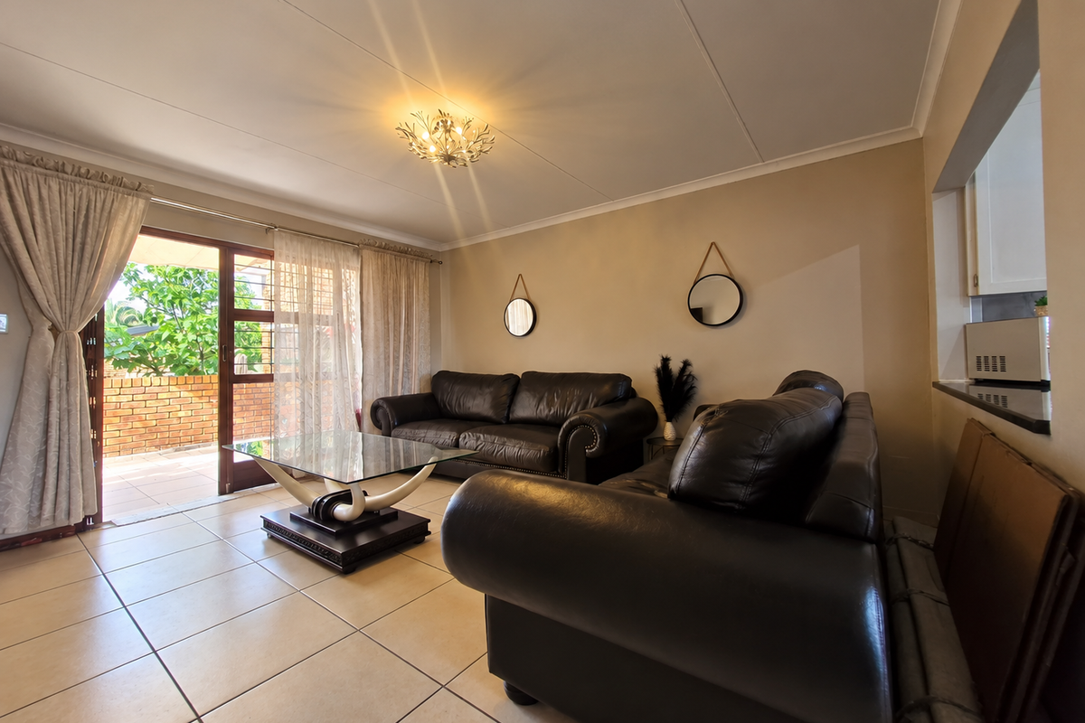 A living room featuring tiled flooring, a coved ceiling, and a sliding glass door providing access to an outdoor patio area.