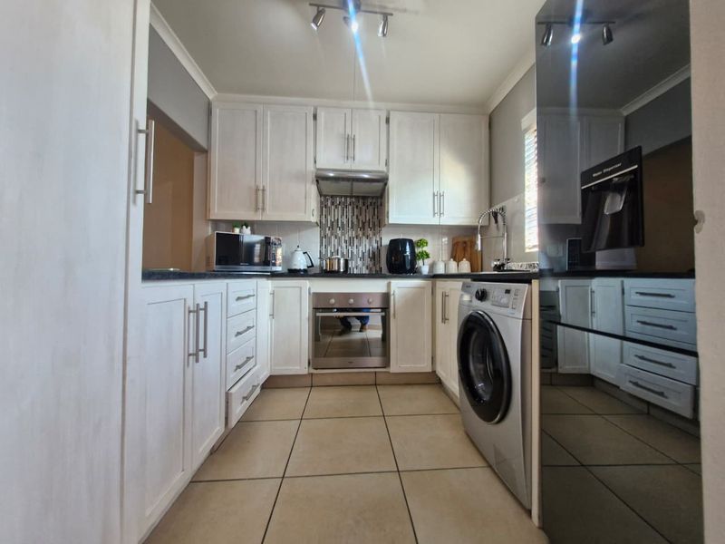 A functional kitchen featuring white built-in cabinetry, tiled flooring, a built-in oven, extractor fan, and a tiled backsplash.