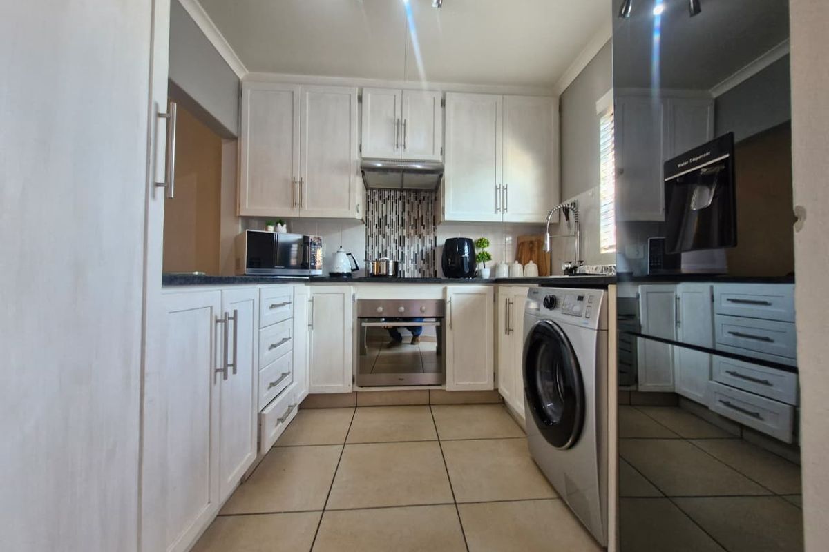 A functional kitchen featuring white built-in cabinetry, tiled flooring, a built-in oven, extractor fan, and a tiled backsplash.