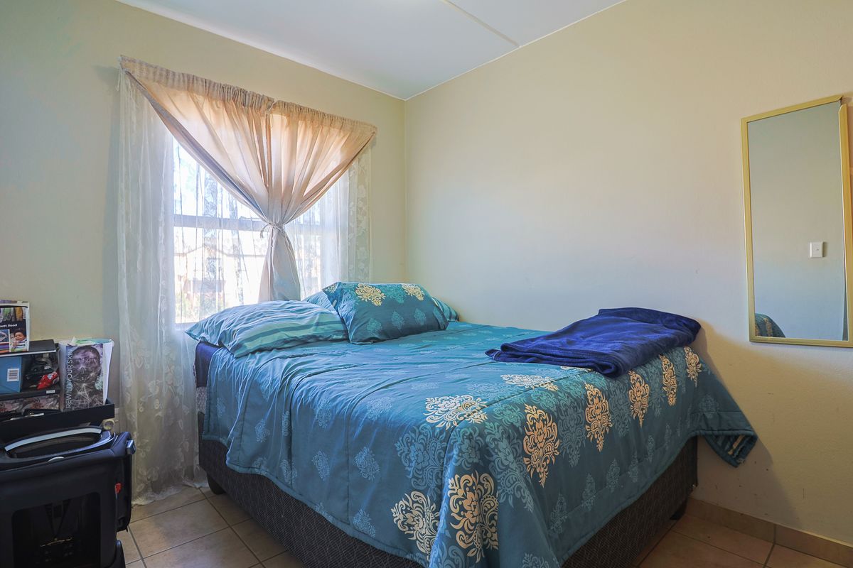 A functional bedroom featuring tiled flooring and a window with natural light, providing a neutral space ready for personalization.