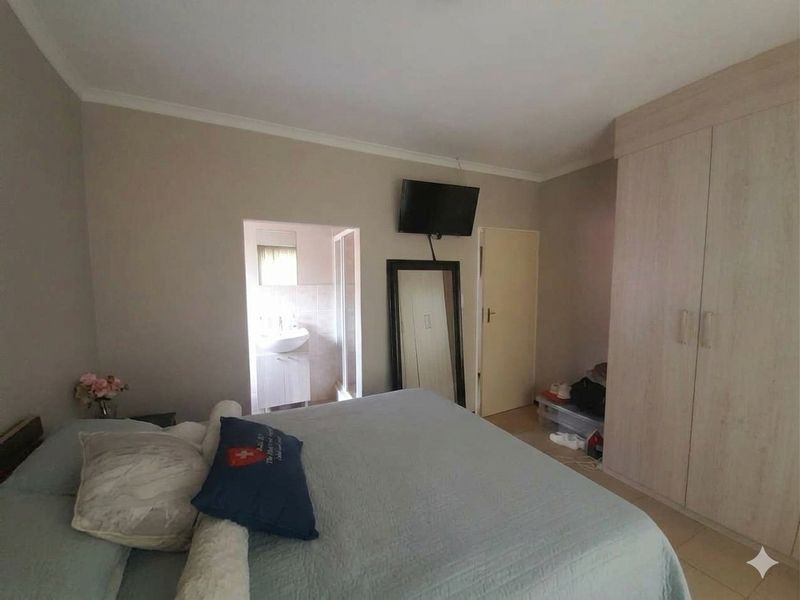 A bedroom featuring built-in wardrobes, tiled flooring, and direct access to an en-suite bathroom.