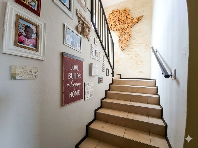 A well-maintained interior staircase featuring tiled steps, a metal balustrade, and a wall-mounted handrail leading to the upper level.