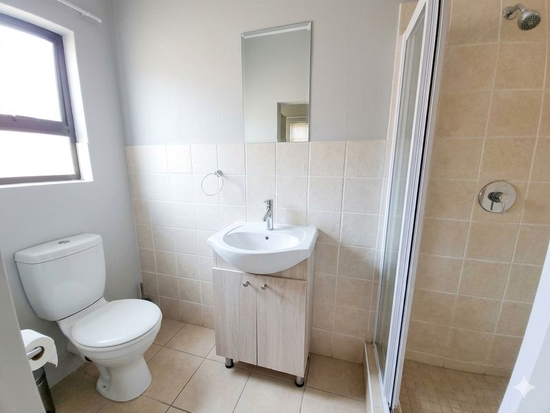 A clean, functional bathroom featuring a vanity cabinet with basin, a toilet, and a separate shower enclosure with tiled finishes.