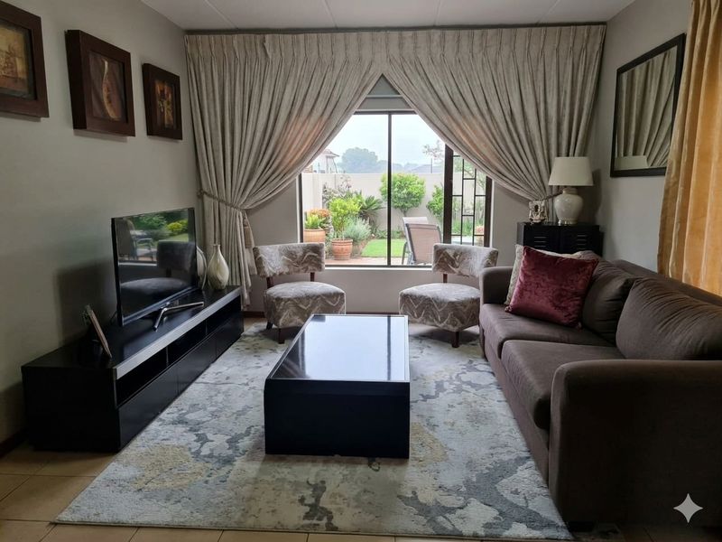 A comfortable living room featuring tiled flooring and a large sliding glass door that provides natural light and access to the rear garden.