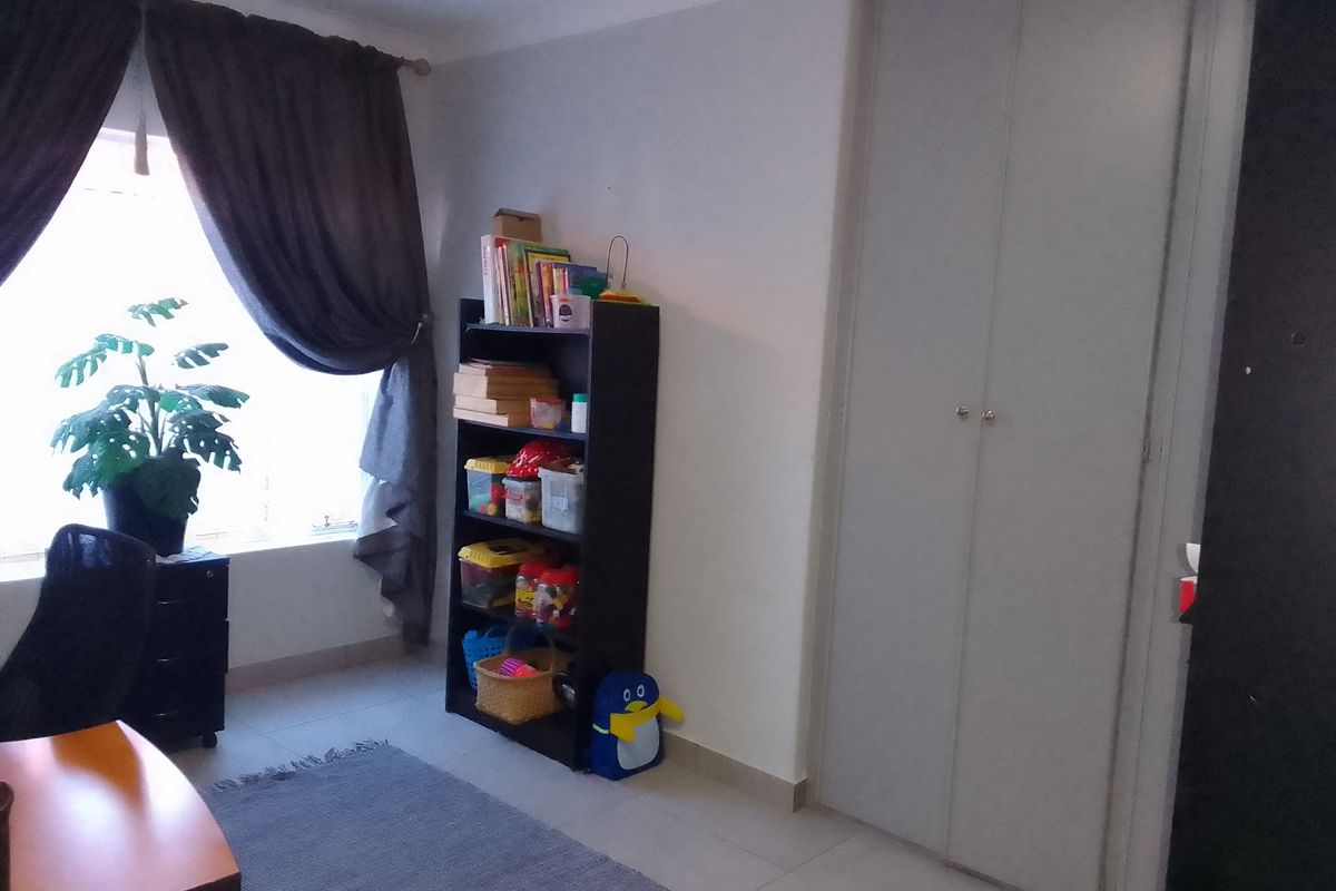 A bedroom featuring tiled flooring, a built-in wardrobe, and a window with curtains.