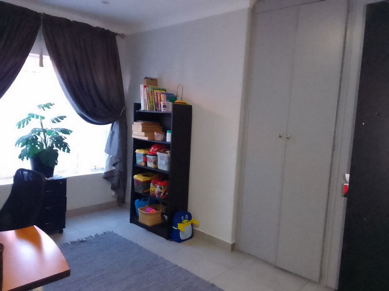 A bedroom featuring tiled flooring, a built-in wardrobe, and a window with curtains.