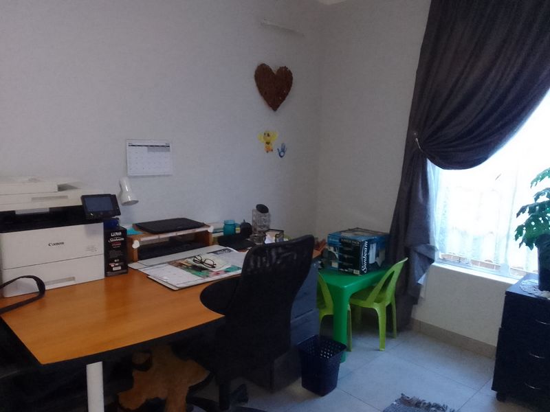 A functional home office space featuring tiled flooring and a window with curtains, providing a practical area for work or study.
