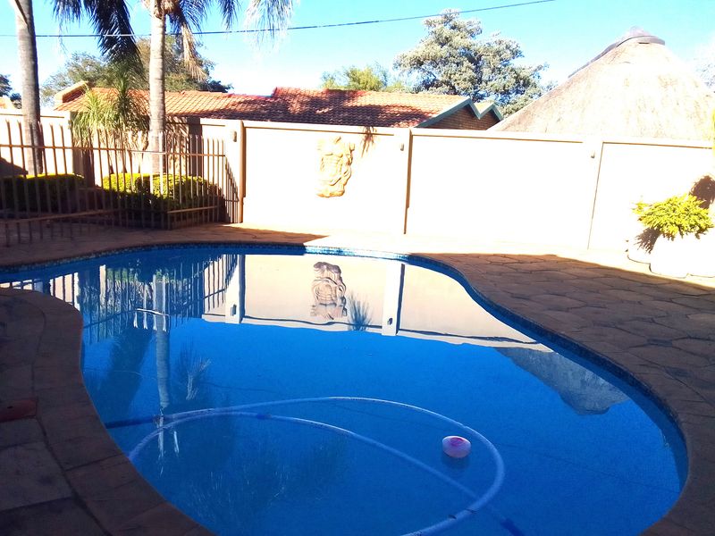 A private swimming pool area featuring paved surrounds, a boundary wall, and metal fencing.