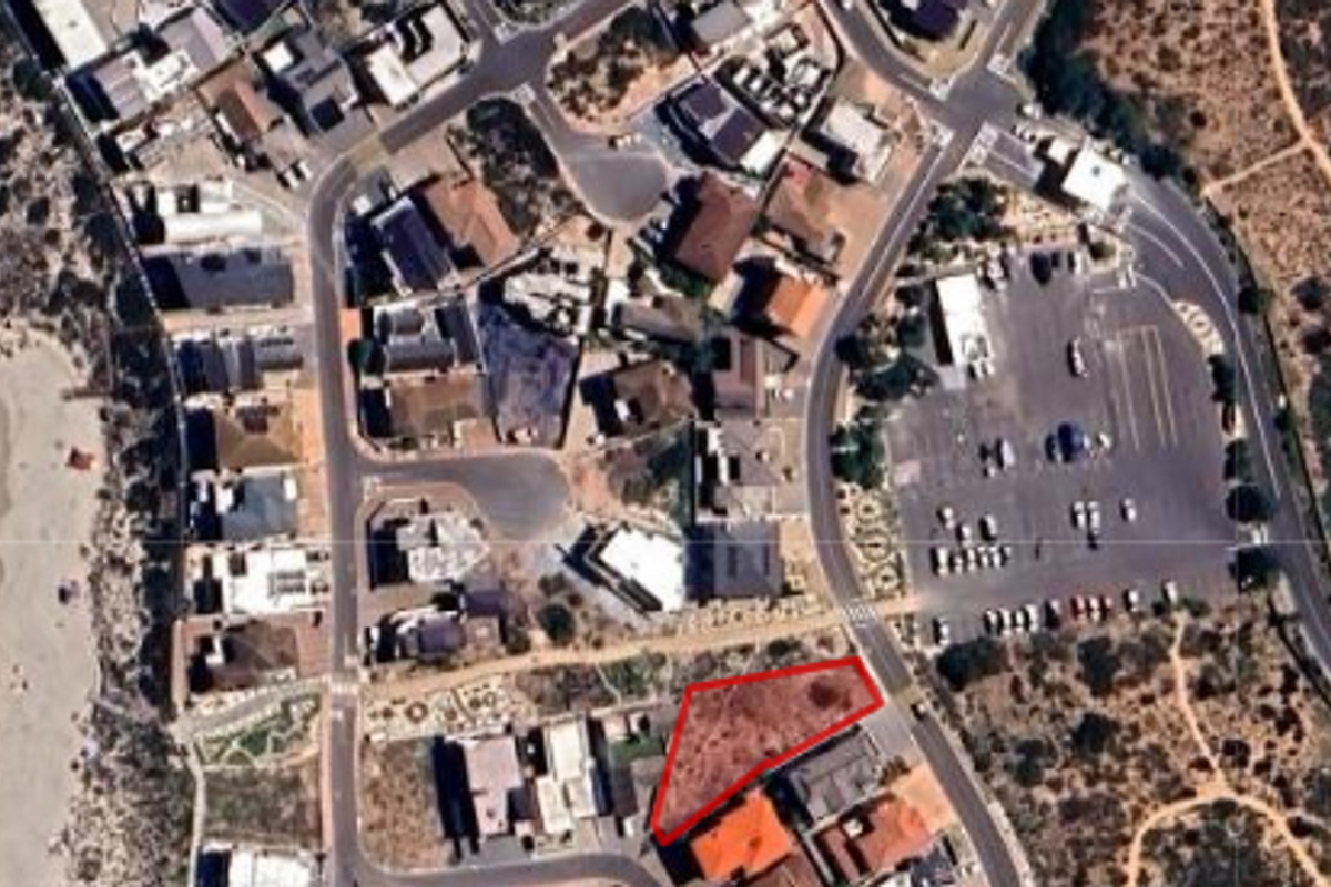 Aerial view of a vacant residential land plot situated in a coastal neighborhood, highlighting the property boundaries and surrounding infrastructure.