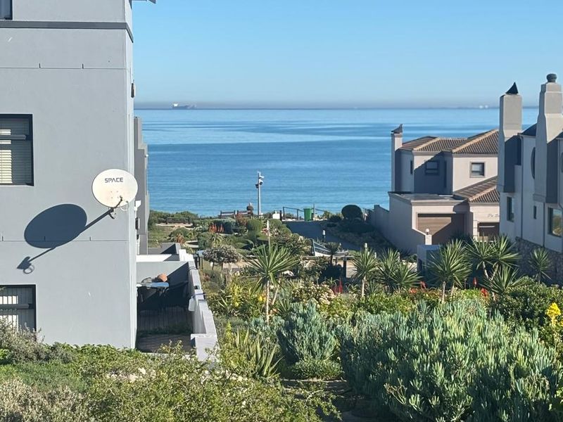 A scenic view overlooking the ocean, featuring landscaped coastal gardens and surrounding residential architecture.
