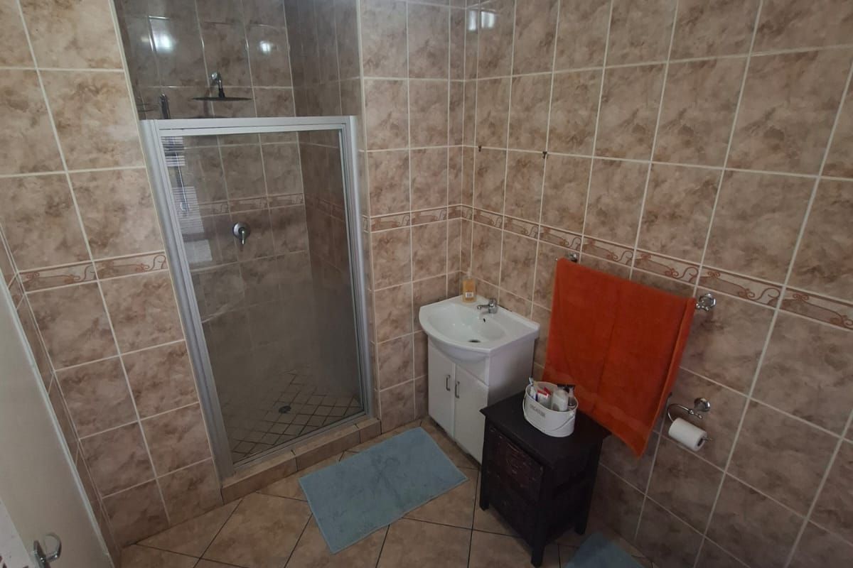A functional bathroom featuring a corner bathtub, separate shower enclosure, vanity basin, and toilet, finished with neutral ceramic wall and floor tiling.
